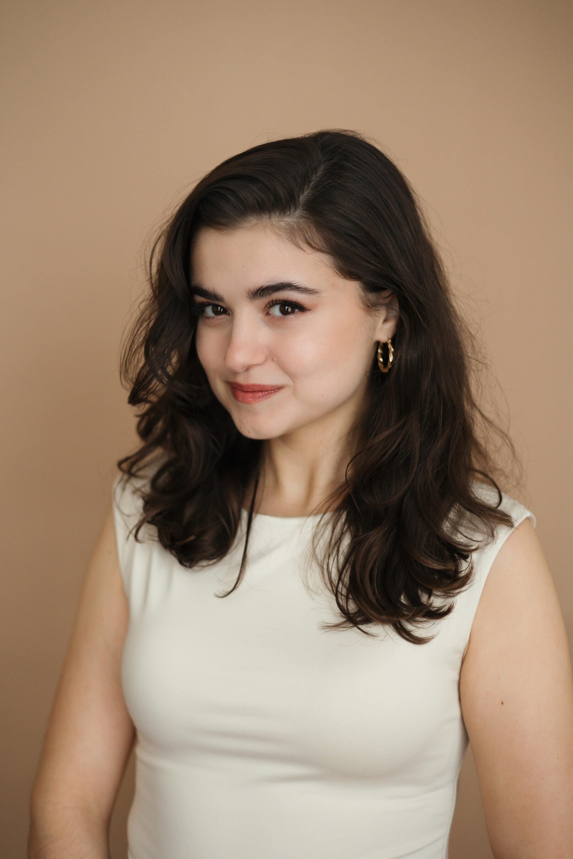 Musician headshot of a soprano taken in a studio in front of a tan background.